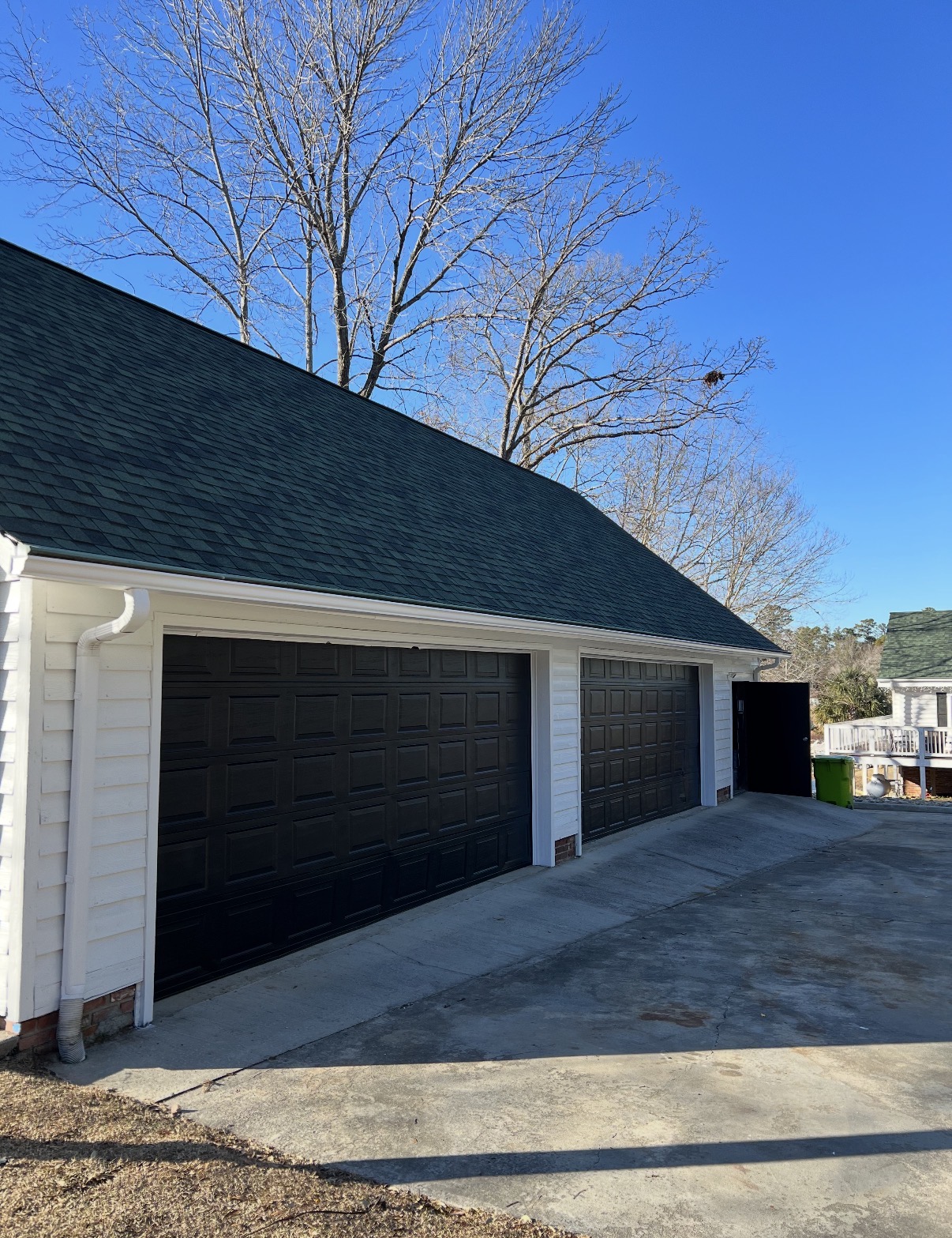 Garage doors refinished in rich black against crisp white horizontal siding