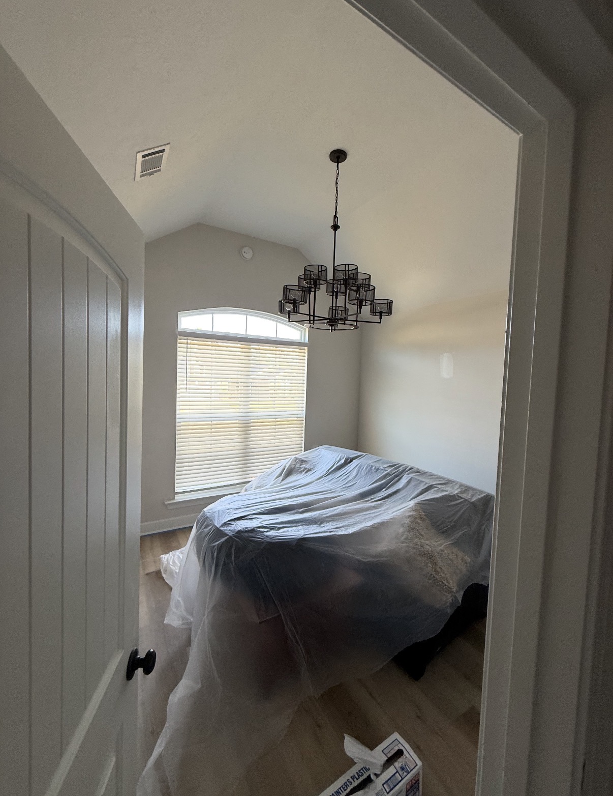 Bedroom fully masked with plastic sheeting and floor protection before interior painting