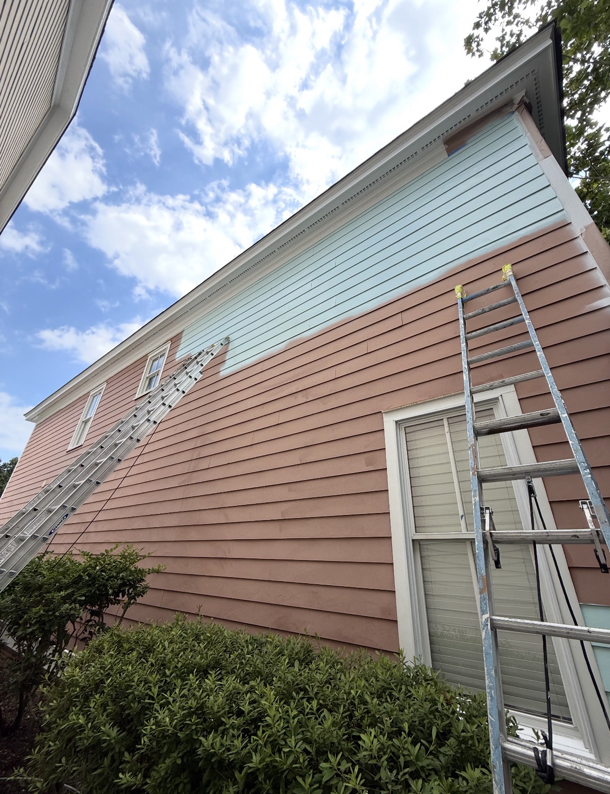 Before: Close-up of historic wood siding mid-repaint with a ladder set against the house — Full Exterior Color Change, Exterior Painting by CJC Remodeling