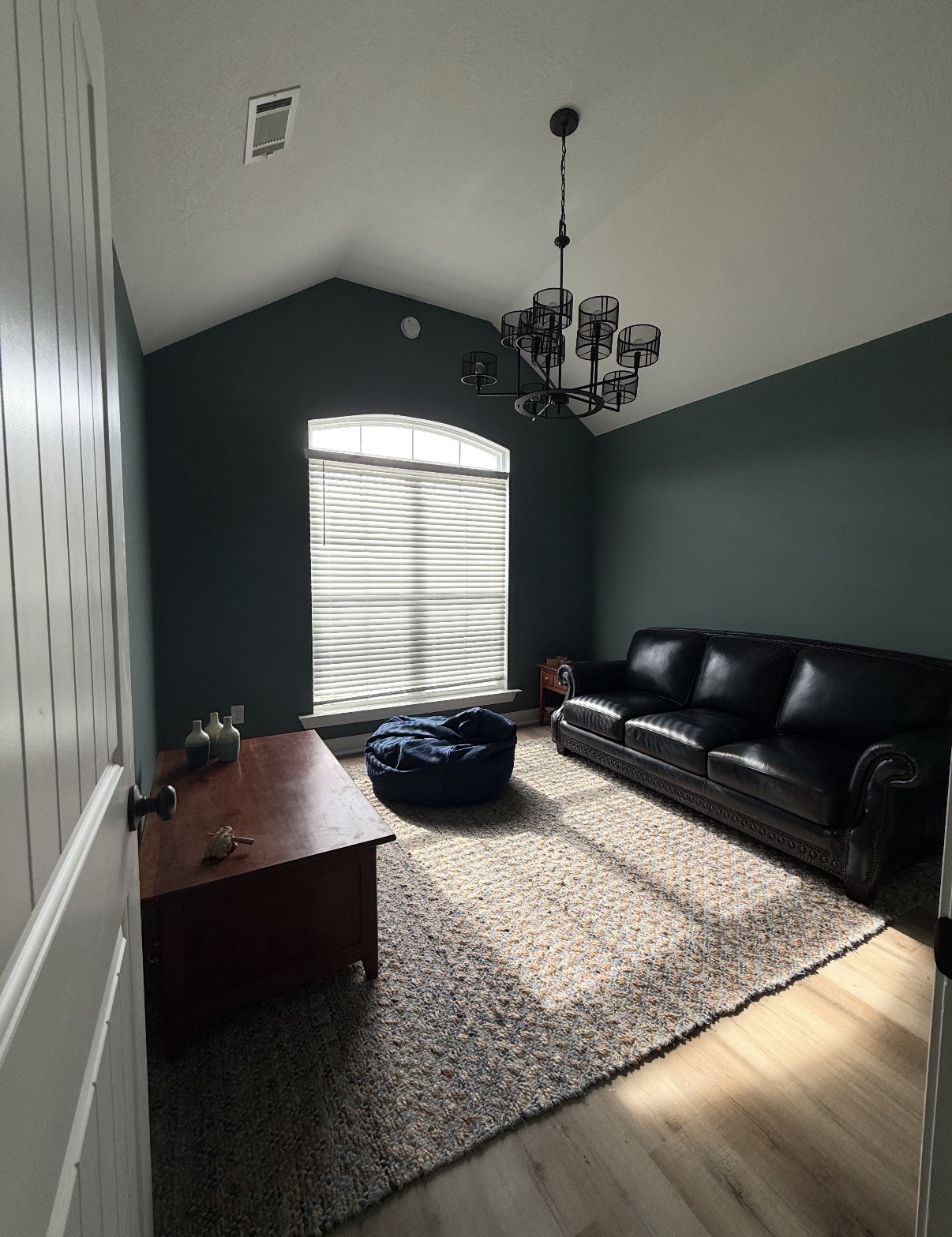 Modern living room with deep green accent walls, new flooring, and a leather sofa